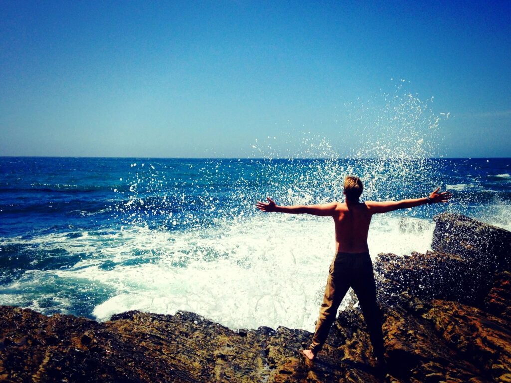 person on rock with arms out